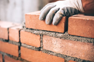 IWM-Aktuell iStock-622800884-300x200 Close up of industrial bricklayer installing bricks on construction site  